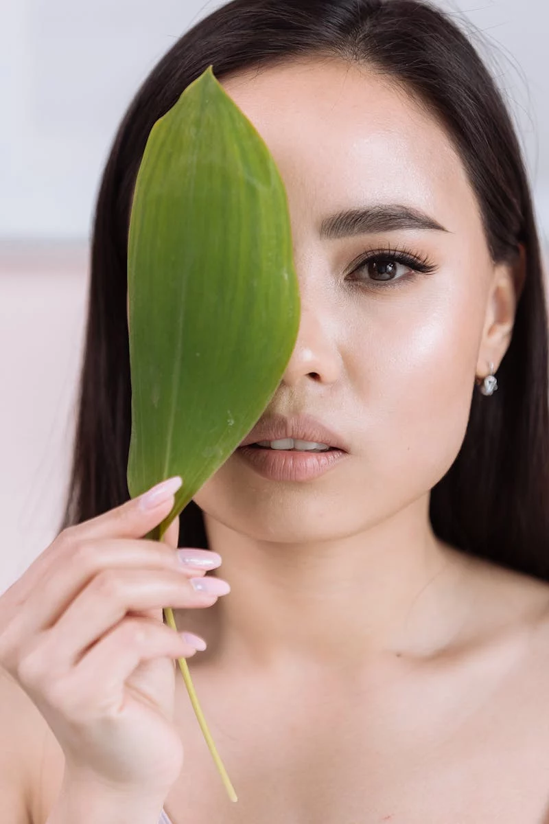 Sophisticated portrait of a woman holding a leaf, exuding elegance and minimalism.